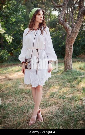 Mode extérieur: La belle jeune fille boho (hippie) dans grove (forêt). Portrait d'une femme adorable en robe blanche Banque D'Images