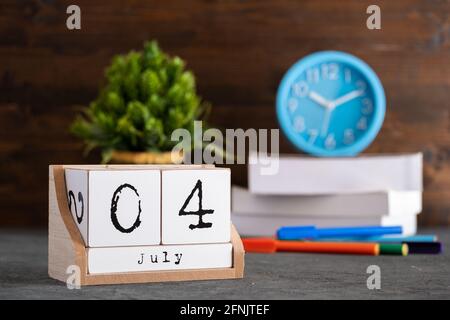 Le 04 juillet. Juillet 04 calendrier cube en bois avec des objets flous sur fond. Banque D'Images