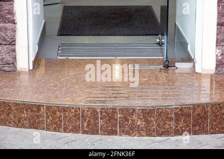 seuil de granit de carreaux de pierre entrée de magasin avec porte en verre et tapis ​with pied tapis près, personne Banque D'Images