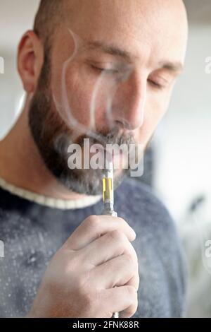 homme vaporant du distillat de cannabis avec un stylo de vape Banque D'Images