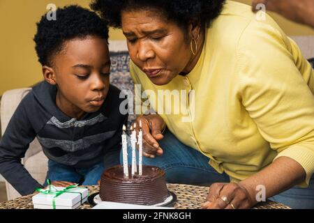 Grand-mère et petit-fils soufflent des bougies sur le gâteau d'anniversaire à la maison Banque D'Images