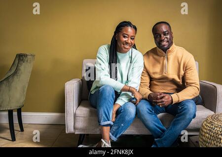 Portrait d'un couple mûr souriant assis sur un canapé à la maison Banque D'Images