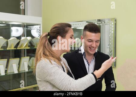 Jeune couple attrayant inspectant la sélection de bracelet pendant son amour Petit ami debout au magasin de bijoux Banque D'Images