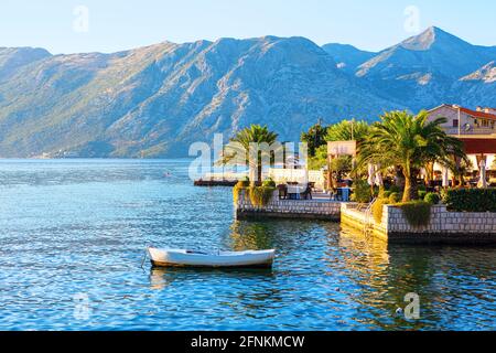 Terrasse de restaurant côtière sur la plage tropicale. Terrasse de café donnant sur la baie de Kotor au Monténégro. Bateau blanc amarré Banque D'Images