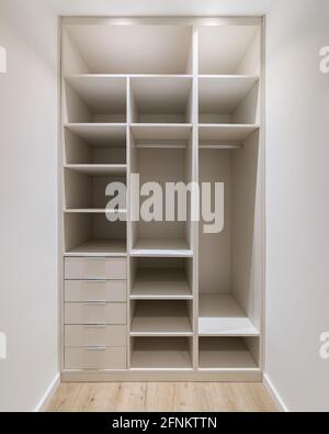 Nouveau mobilier intégré dans un petit dressing. Ce local moderne comprend une armoire, de nombreuses étagères et de nombreux tiroirs Banque D'Images