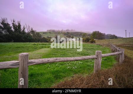 Paysage de terres agricoles d'un pays avec un chalet à l'arrière-plan sur un matin brumeux. Banque D'Images