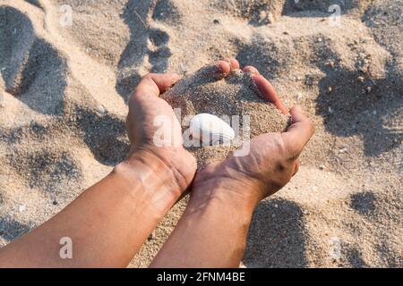 Coquillages et sable dans les mains arrière-plan Banque D'Images