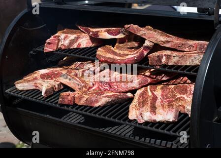 Assortiment de portions de côtes levées grasses assaisonnées brutes prêtes à l'emploi Le barbecue a rempli sur les étagères du gril à l'extérieur, en gros plan Banque D'Images