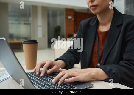 Gros plan de la jeune femme d'affaires utilisant un ordinateur portable pour travailler en ligne pendant travailler sur son lieu de travail Banque D'Images