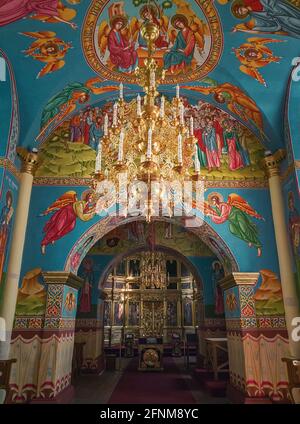 Beaux murs peints et plafond à l'intérieur du monastère de Capriana. Lustre doré avec lumières brillantes. Différentes icônes des saints comme la trad Banque D'Images