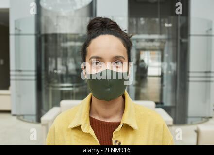 Portrait d'une jeune femme d'affaires dans un masque de protection regardant l'appareil photo debout au bureau Banque D'Images