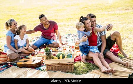 Des familles multiraciales heureuses qui prennent le selfie à la fête du jardin pic nic - concept de joie et d'amour multiculturel avec des gens de race mixte s'amuser ensemble Banque D'Images