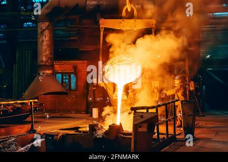 Verser le métal fondu dans le moule à partir du conteneur de louches dans l'atelier de fonderie de l'usine métallurgique, fonte, arrière-plan industriel lourd. Banque D'Images