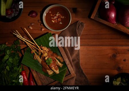 Vue de dessus du satay de porc grillé (Moo Satay) servi avec de la sauce aux arachides sur la table avec des ingrédients Banque D'Images