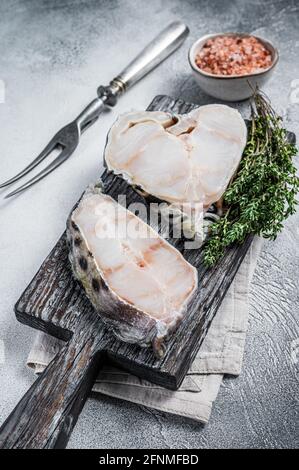 Filet de loup de mer cru Steak sur planche à découper en bois. Arrière-plan blanc. Vue de dessus Banque D'Images