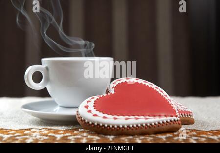 Pour vous. Café cuit à la vapeur dans une tasse sur la table à côté de deux biscuits en forme de coeur de pain d'épice Banque D'Images
