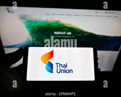 Personne détenant un smartphone avec le logo commercial de la société de fruits de mer Thai Union Group plc à l'écran devant le site Web. Concentrez-vous sur l'affichage du téléphone portable. Banque D'Images