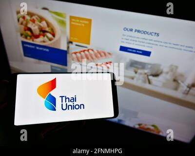 Personne tenant un smartphone avec le logo de la société de fruits de mer Thai Union Group plc sur l'écran devant le site Web. Mise au point sur l'affichage du téléphone. Photo non modifiée. Banque D'Images