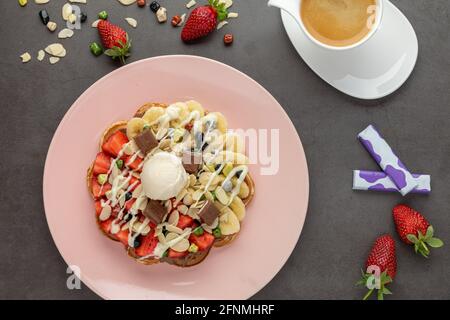 Gaufre de coeur avec banane et fraise avec bonbons délicieux et glace sur elle. Banque D'Images