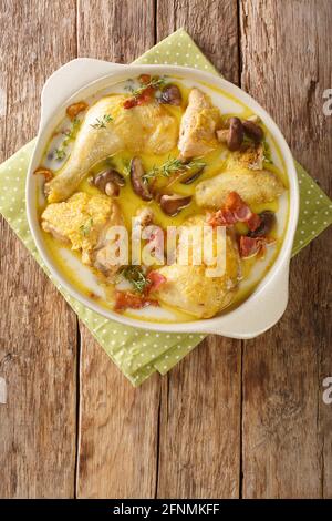 Alsace Coq au vin Riesling poulet au vin blanc avec crème et champignons gros plan dans une casserole sur la table. Vue verticale du dessus Banque D'Images