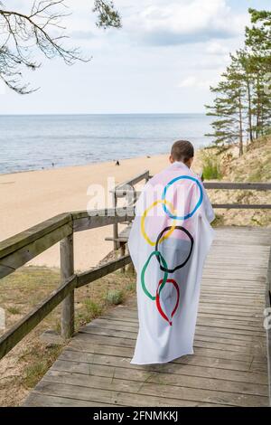 Riga, Lettonie, mai 16. 2021. Garçon avec drapeau des Jeux Olympiques. Symbole de cinq anneaux Banque D'Images