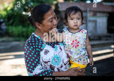 Bali, Indonésie - 4 septembre 2016 : une femme âgée non identifiée portant un tout-petit. Banque D'Images