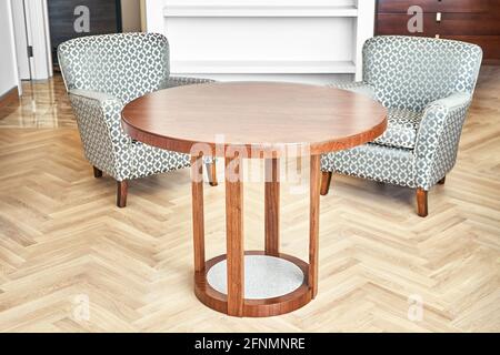 Table à café laquée classique en placage marron et solide pièce en noyer et acrylique à proximité de fauteuils confortables dans la salle de séjour Banque D'Images