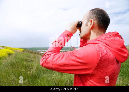Homme randonnée et observation des oiseaux regardant à travers des jumelles Banque D'Images