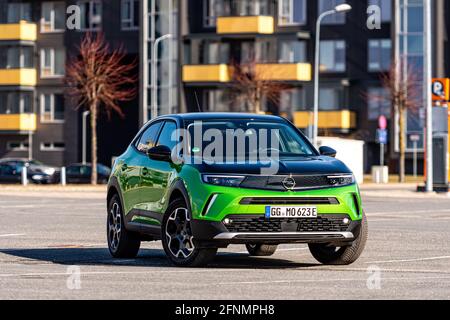 Riga, Lettonie - 26 mars 2021: Véhicule électrique vert Opel Mokka-e dans le parking sur le fond d'une zone résidentielle urbaine Banque D'Images