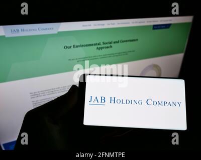 Personne détenant un smartphone avec le logo du conglomérat d'affaires JAB Holding Company S.à r.l. à l'écran devant la page Web. Concentrez-vous sur l'affichage du téléphone portable. Banque D'Images