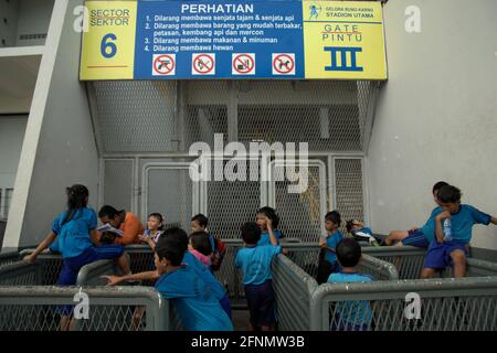 Un enseignant accompagne les élèves du primaire dans l'apprentissage en plein air après une séance de sport à l'extérieur du stade principal Senayan (stade Gelora Bung Karno) à Jakarta, en Indonésie. Banque D'Images