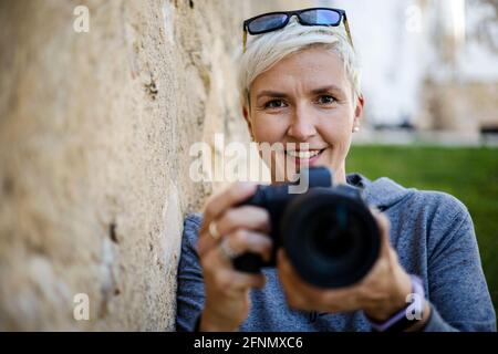 Portrait d'une femme positive avec l'appareil photo numérique dans elle mains Banque D'Images