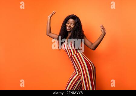 Photo de joyeuse charmante belle peau sombre femme lever les mains danse d'été de rêve isolée sur fond de couleur orange Banque D'Images