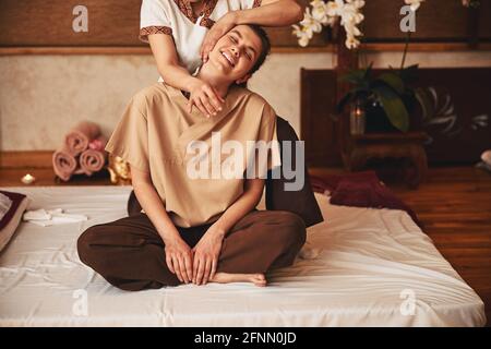 Une femme ravie de se détendre sous un massage thaï de yoga Banque D'Images