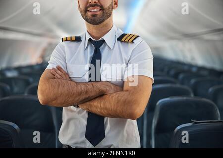 Homme confiant pilote gardant ses bras croisés dans l'avion Banque D'Images