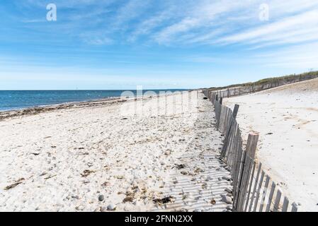 Plage de sable déserte adossée à des dunes et à l'océan bleu un jour d'automne ensoleillé Banque D'Images