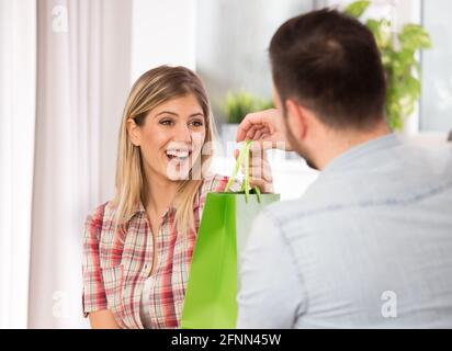 Jeune homme beau donnant sac de shopping comme présent à lui petite amie surprise Banque D'Images