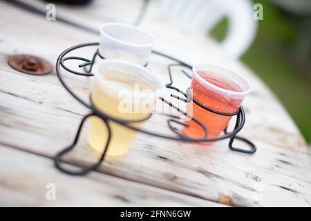 Trois petits verres de cidre coloré, aux couleurs différentes, sur une table en bois lors d'une fête dans le jardin ou d'une dégustation Banque D'Images