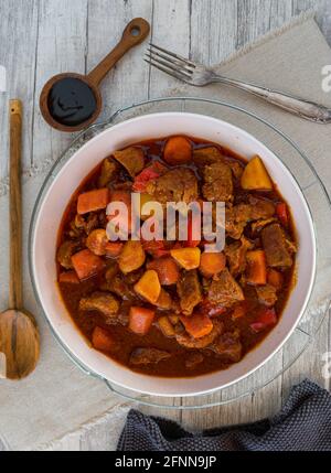 ragoût de porc épicé avec légumes et pommes de terre servi sur fond de bois blanc. vue sur le dessus Banque D'Images