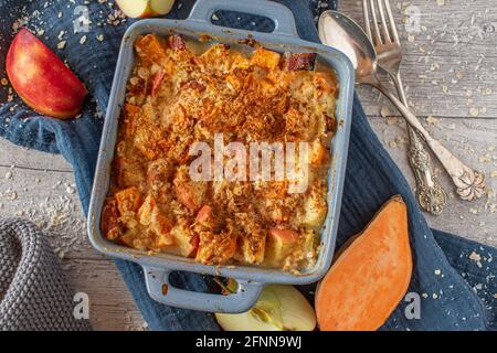 Cocotte de patate douce, pomme et flocons d'avoine avec fromage cottage et nappée de noix de coco râpée servie sur fond de table rustique en bois. Vue de dessus Banque D'Images