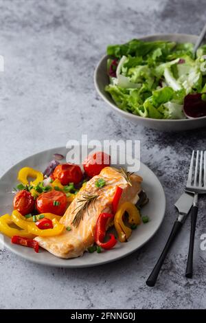 Filet de poisson rouge cuit omble chevalier sur une assiette de légumes, mélanger la salade dans un bol, délicieux repas sain et copieux Banque D'Images