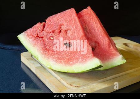Pastèque mûre sur une planche en bois dans la cuisine. Nourriture sur fond noir Banque D'Images