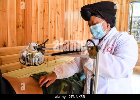 Nanning, Chine. 18 mai 2021. (210518) -- NANNING, le 18 mai 2021 (Xinhua) -- Pan Jiping effectue de la physiothérapie à un villageois du village de Xiaozhai, dans le canton de Longji, comté de Longsheng, région autonome de Guangxi Zhuang, dans le sud de la Chine, le 18 mai 2021. À Xiaozhai, un village au pied de la montagne de Fupingbao à plus de 1,900 mètres d'altitude, Pan Jiping est médecin de campagne ici depuis plus de 30 ans. PAN, 57 ans, est l'un des Hongyao, une branche du groupe ethnique Yao. Banque D'Images