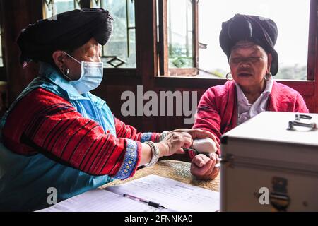 Nanning, Chine. 18 mai 2021. (210518) -- NANNING, 18 mai 2021 (Xinhua) -- Pan Jiping vérifie la pression artérielle d'un villageois au village de Xiaozhai, canton de Longji, comté de Longsheng, région autonome de Guangxi Zhuang, dans le sud de la Chine, le 18 mai 2021. À Xiaozhai, un village au pied de la montagne de Fupingbao à plus de 1,900 mètres d'altitude, Pan Jiping est médecin de campagne ici depuis plus de 30 ans. PAN, 57 ans, est l'un des Hongyao, une branche du groupe ethnique Yao. Banque D'Images