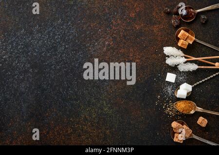 Sucre blanc, cubes de sucre de canne, caramel en cuillères à café sur fond de béton de table brun foncé. Différents types de sucre assortis. Vue de dessus ou plan de travail. Banque D'Images