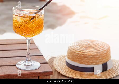 Un verre d'aperol Spritz, chapeau de paille et lunettes de soleil sur la plage Banque D'Images