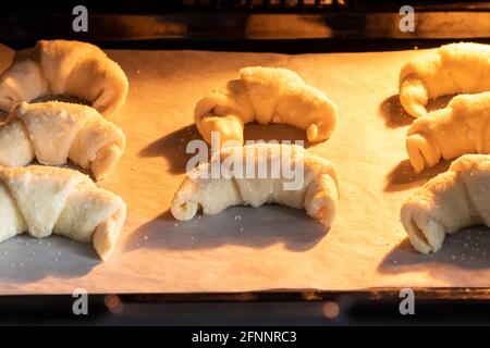 Croissants à sucre dépoli cuits au four sur une plaque de cuisson recouverte de papier parchemin. Petits pains sucrés d'une pâte au fromage cottage cuite dans un four chaud. Le Banque D'Images