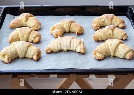 Croissants cuits à partir d'une pâte au fromage cottage avec du sucre sur une plaque de cuisson sur un tabouret en bois juste sorti du four. En-cas pour le petit-déjeuner. Le p Banque D'Images