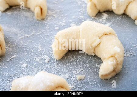 Vue rapprochée d'un bagel préparé pour la cuisson une pâte à caillé saupoudrée de sucre couché sur une pâte feuille recouverte de papier sulfurisé et c Banque D'Images