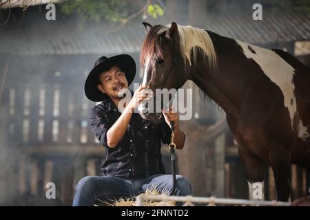 Fermier assis et la main touchant le cheval dans le ranch. Banque D'Images